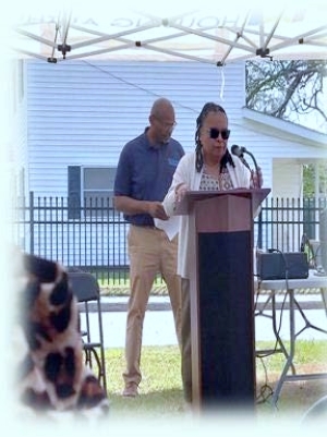A lady in a light shirt and tan pants speaking at a podium.