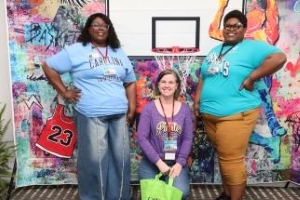 Three ladies posing with a basketbal hoop.