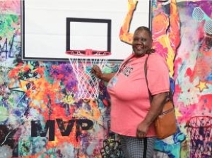 Ladies in a pink shirt standing with a basketball hoop.
