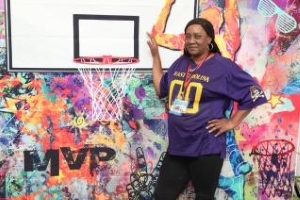 Ladies in a purple shirt standing with a basketball hoop.