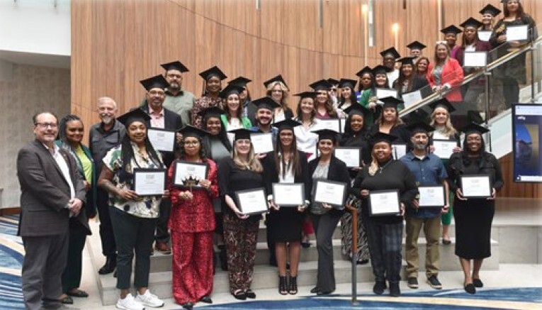 graduates standing on a staircase and smiling for a picture.