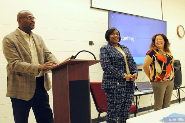 A man speaking at a podium with two women standing beside him.