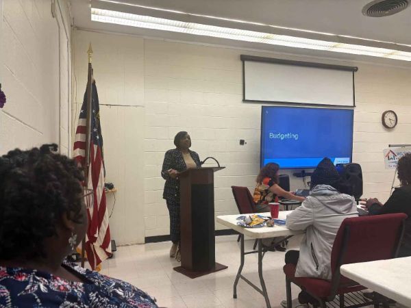 A woman speaking at the podium to a room of people.