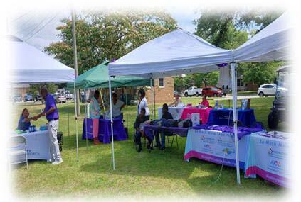 People standing around multiple tables setup at the Elder Abuse Awareness event.