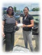 Two women smiling and holding a to go box.