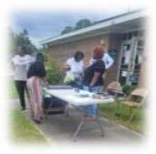 People standing around a table outside.