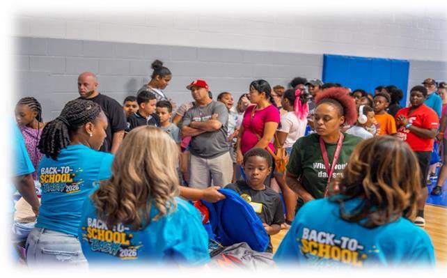 Back to School Bash workers handing out backpacks to a line of people.