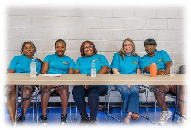Back to school Bash workers sitting behind a table smiling for a picture.