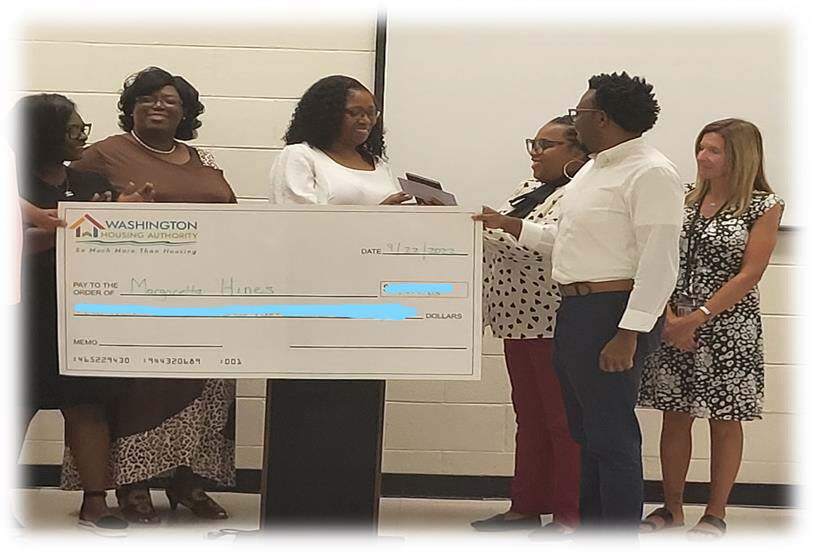Several people are gathered around a large check that is being presented to Margaretta Hines.