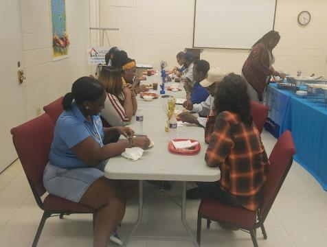 Various people are gathered together at a table, sharing a meal together.