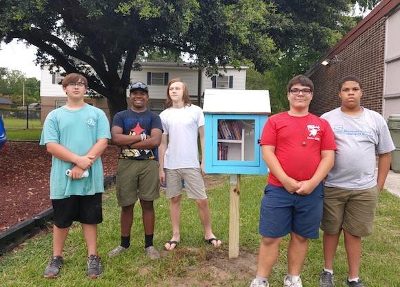Egal Scouts Troop 21 members stand next to the little library they just gifted to WHA.