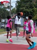 A group of people are playing a game of basketball, one person is jumping in the air to dunk the ball.