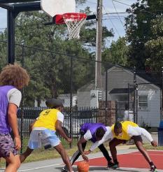 Two basketball players are running towards the ball with their arms out.