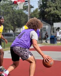 A person dribbles the basketball down the court and towards the basket.