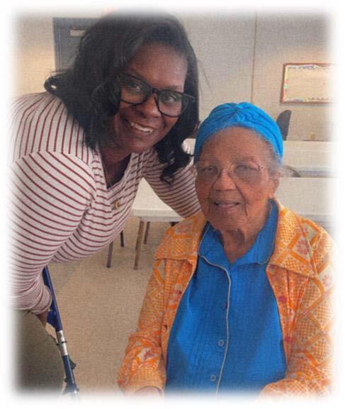 A woman leans down to put her arm around Lillian Boyd and both of them smile for the camera.