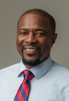 A man in a tie smiling at the camera.