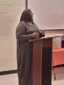 A woman in a dress talking to students.