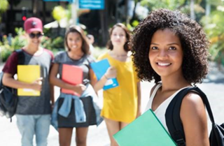 Young woman holding school books and her peers behind her. 