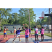 Kids in pink, purple, and orange jerseys standing around the free throw line practicing