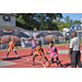 Kid in a pink jersey is bouncing the ball while kid in an orange jersey guards him