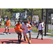 The player in the white jersey has the ball and the two players in orange jerseys try to get it