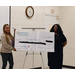 Two women standing by a big check