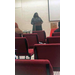 A woman wearing pearls is speaking to the people seated in the room from the podium. 