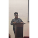 A woman in black-rimmed glasses speaks from the podium. 