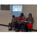 A group of three sit at a desk taking notes.