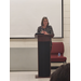 A women stands behind a podium while lecturing.