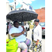 Two individuals sit under an umbrella.