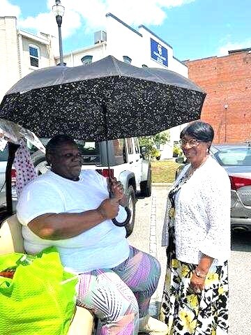 Two individuals sit under an umbrella.