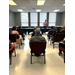 A view from the back of a meeting room with a speaker at the front.