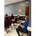 A woman sits in the back of a room listening.