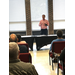 A speaker talks to a group of people in the front of a room.