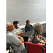 Four people sitting at tables while listening to a presentation.