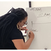 A woman writing on a piece of paper on an easel.