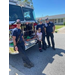 A girl smiling with several fire fighters.