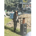 A lady talking at a podium outside.