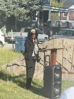 A lady talking at a podium outside.