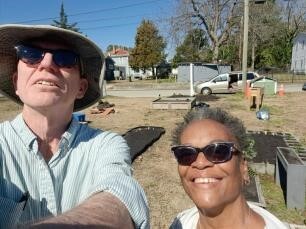 Two people with the community garden in the background.
