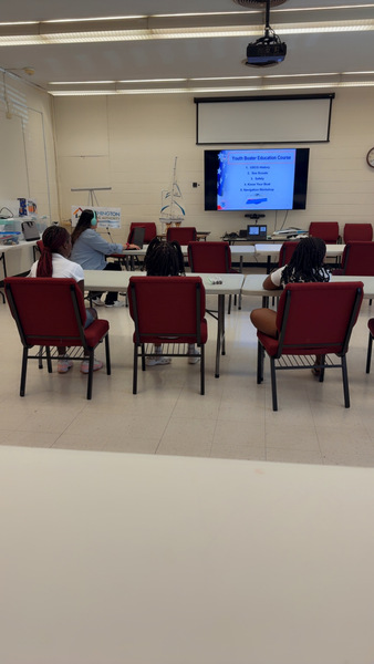 1000016067.jpg Three students sit at a table looking at a screen on the wall that says Youth Boater Education Course. 1. USCG History. 2. Sea Scouts 3. Safety 4. Know Your Boat 5. Navigation Workshop.