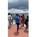  A group of people standing by the water with a gazebo in the background. 