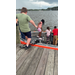  Three kids standing in the boat, while another gets in. 