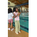  Two girls stand outside a pool using remote controlled boats. 