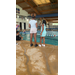  Two girls standing by the pool, with one sitting close by. 