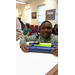  A young boy smiles holding his art project boat. 