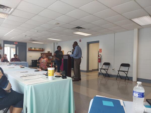 20250618151049.jpg Jordan Distance talking to two men up at the podium.