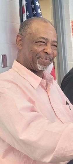 A man smiling, up against a wall.