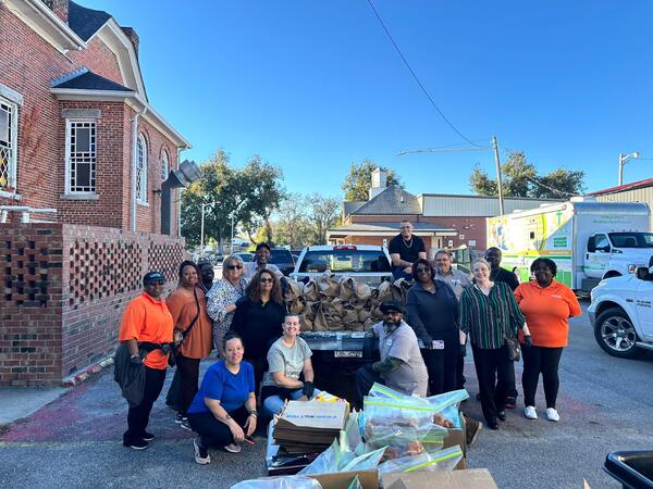A group of people gather around a truck that is full of bags of food that will be distributed.